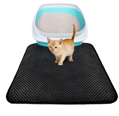 Cat stepping off a black double-layer honeycomb litter trapping mat beside a litter box