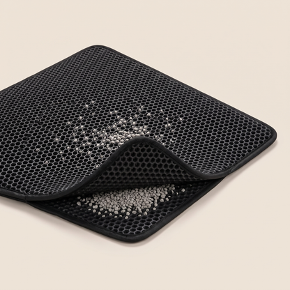 Black double-layer honeycomb litter mat folded at the corner to show litter trapped between the two layers